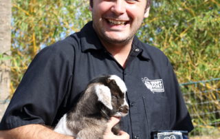 Brian Abernathy, founder and master roaster of Grumpy Goat Coffee holding a goat